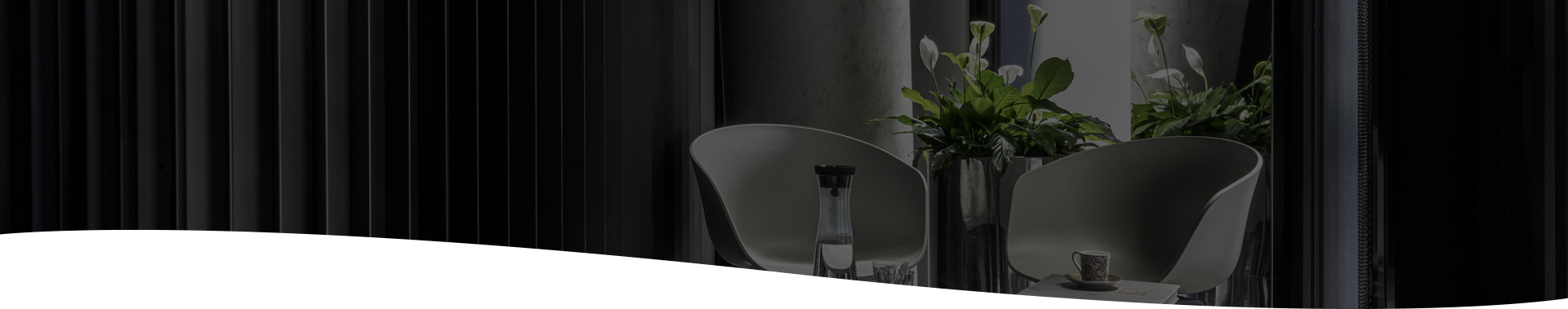 Designová odpočinková zóna Cellularia – dvě moderní židle, stolek s karafou vody, šálkem kávy a čerstvými rostlinami.
