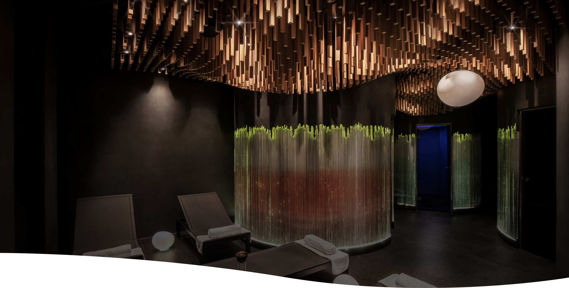Designový interiér Cellularia – kruhový prostor s lehátky, světelnými instalacemi a dřevěným stropem pro klidnou relaxaci.